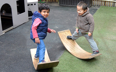 boys balancing on curved wood at daycare