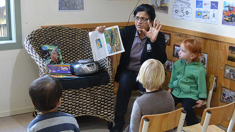 teacher reading a book to children at daycare