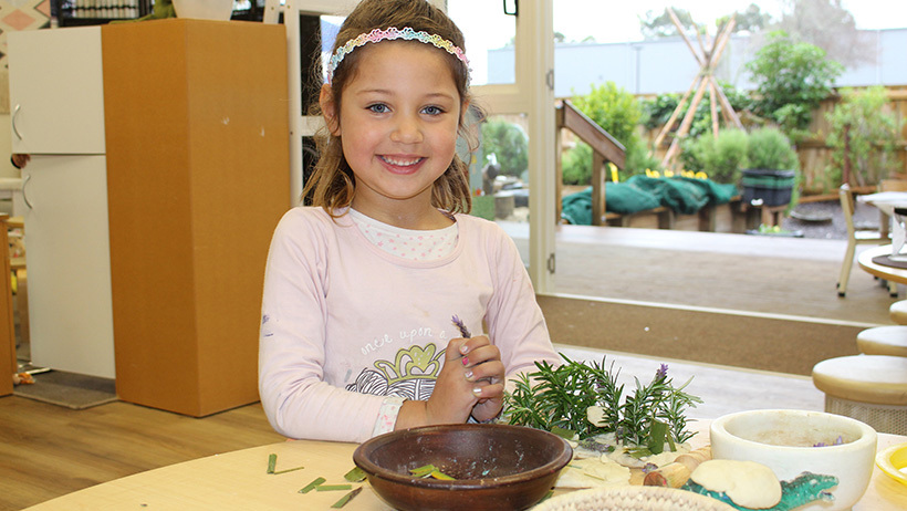 girl playing with plant mixture at daycare